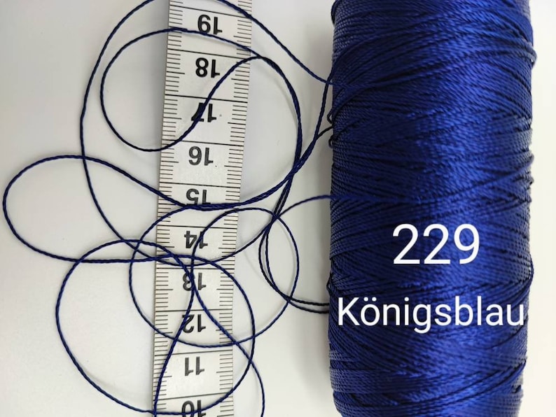 Puede incluir: Una bobina de hilo azul oscuro con el n&uacute;mero 229 y la palabra "K&ouml;nigsblau" impresa en ella.