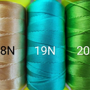 Può includere: Tre bobine di filo, una dorata, una turchese e una verde. Le bobine sono etichettate con 18N, 19N e 20N.