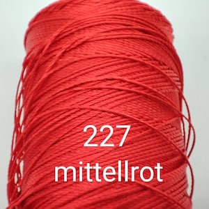 Puede incluir: Una bobina de hilo rojo con el n&uacute;mero 227 y la palabra "mittelrot" impresa en ella.