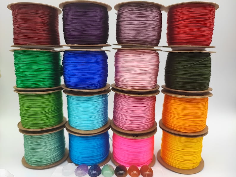 May include: A collection of 14 spools of colorful waxed cord, each wound with a different color of thread. The colors include red, purple, pink, green, blue, turquoise, and yellow.