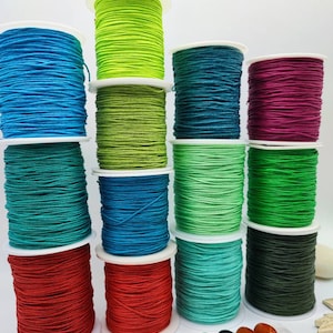 Può includere: Assortimento di bobine di cordoncino di cotone cerato colorato, perfetto per la creazione di gioielli, macramé e artigianato. Le bobine sono disposte in fila, ogni bobina presenta un colore vibrante diverso.