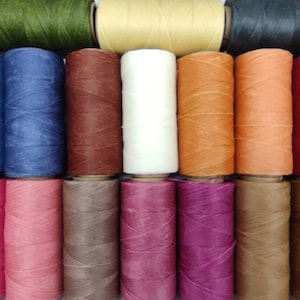 May include: Assortment of 18 spools of waxed thread in various colors, including green, blue, red, brown, pink, and orange. The spools are arranged in three rows of six.