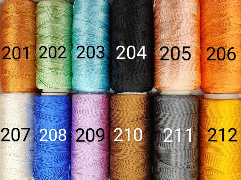 Puede incluir: Una colecci&oacute;n de 12 carretes de hilo en varios colores, incluyendo naranja, verde, azul, blanco, negro, marr&oacute;n, gris y amarillo. Los carretes est&aacute;n numerados del 201 al 212.