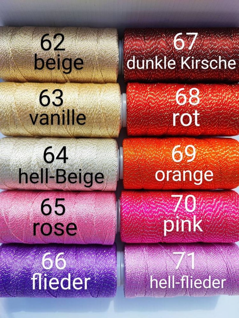 May include: Close-up of ten spools of embroidery floss in various colors, including beige, vanilla, rose, pink, and purple. Each spool is labeled with a number and a color name in German.