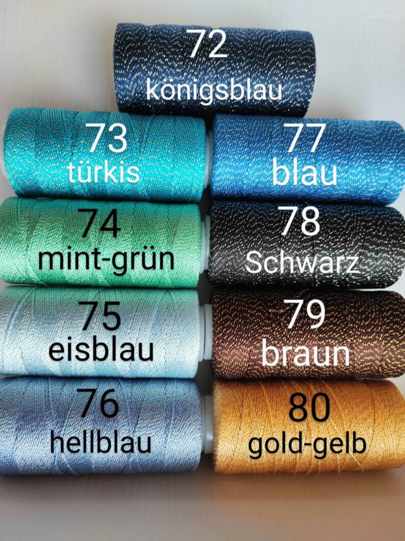 May include: Eight spools of thread with different colors and numbers. The colors are turquoise, mint green, light blue, dark blue, black, brown, gold, and a darker blue. The numbers are 72, 73, 74, 75, 76, 77, 78, 79, 80. The text on the spools reads "k&ouml;nigsblau", "t&uuml;rkis", "mint-gr&uuml;n", "eisblau", "hellblau", "blau", "Schwarz", "braun", and "gold-gelb".