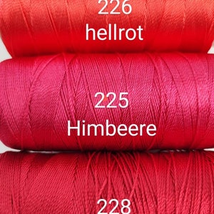 Puede incluir: Tres carretes de hilo de bordar rojo. El carrete superior est&aacute; etiquetado como "226 hellrot", el carrete del medio est&aacute; etiquetado como "225 Himbeere" y el carrete inferior est&aacute; etiquetado como "228 dunkelrot".