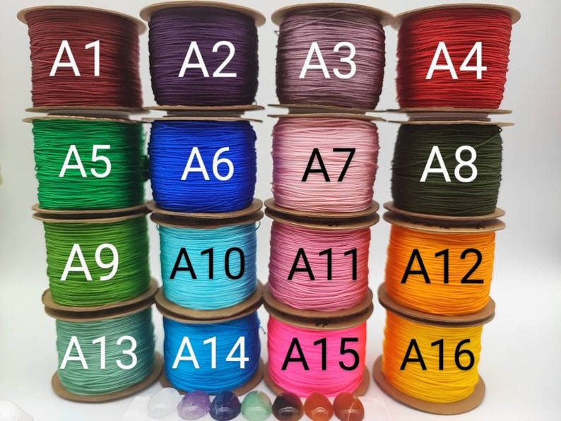 May include: A collection of 16 spools of waxed cord in various colors, labeled A1 through A16. The spools are arranged in four rows of four, with each row containing a different color.