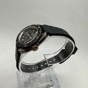 May include: A black and silver wristwatch with a black rubber strap. The watch face has a black background with white numbers and a silver second hand. The watch has a rotating bezel with white numbers.