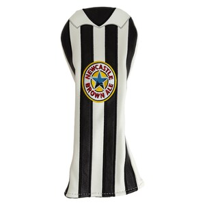 May include: A golf club head cover with a black and white striped design, resembling a soccer jersey. The cover features a circular emblem with the text "Newcastle Brown Ale" and a blue star.