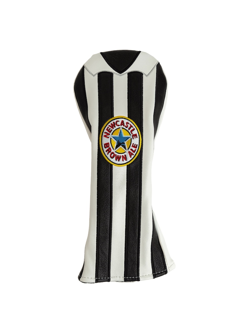 May include: A golf club head cover with a black and white striped design, resembling a soccer jersey. The cover features a circular emblem with the text "Newcastle Brown Ale" and a blue star.