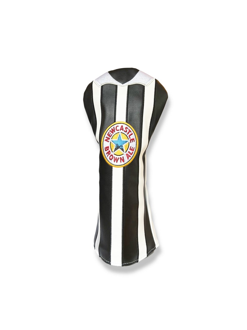 May include: A golf club head cover with a black and white striped design, featuring a Newcastle Brown Ale logo. The cover has a white collar and is made of a leather-like material.