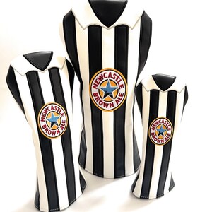 Peut inclure: Trois couvre-chefs de club de golf &agrave; rayures noires et blanches, ressemblant &agrave; un maillot de football. Chacun a un col blanc et un &eacute;cusson circulaire avec "Newcastle Brown Ale" et une &eacute;toile bleue.