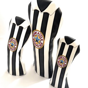 Peut inclure: Trois couvre-clubs de golf &agrave; rayures noires et blanches. Chaque couvre-club arbore un &eacute;cusson circulaire avec les mots "Newcastle Brown Ale" et une &eacute;toile bleue. Les couvre-clubs sont de tailles diff&eacute;rentes.