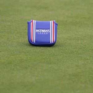 May include: Blue golf club head cover with white and red stripes and the text "McEwan's Lager" in white.