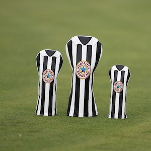 Peut inclure: Trois couvre-clubs de golf avec un motif &agrave; rayures noires et blanches, rappelant un maillot de football. Chaque couvre-club porte un &eacute;cusson circulaire avec une &eacute;toile bleue et l'inscription "Newcastle Brown Ale".