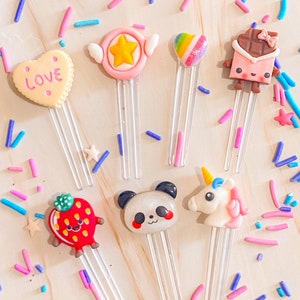 Puede incluir: Seis marcadores de libros coloridos y caprichosos con varios diseños, que incluyen un corazón con la palabra "LOVE", una estrella, un corazón arcoíris, una barra de chocolate, una fresa y un unicornio. Los marcadores están hechos de arcilla polimérica y tienen mangos de plástico transparente.