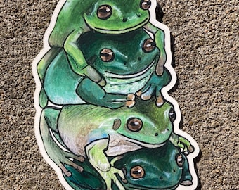 May include: A sticker featuring a stack of four green frogs. The frogs are drawn in a cartoon style with large eyes and are stacked on top of each other.