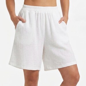 Könnte beinhalten: Weiße Shorts mit einer strukturierten, geknitterten Stoffoberfläche, einem elastischen Bund und zwei Seitentaschen. Das Kleidungsstück hat eine lockere, entspannte Passform, die bis zur Mitte des Oberschenkels reicht und schlicht wirkt.