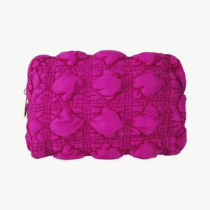 Könnte beinhalten: Eine hellrosa gesteppte Kosmetiktasche mit Reißverschluss.