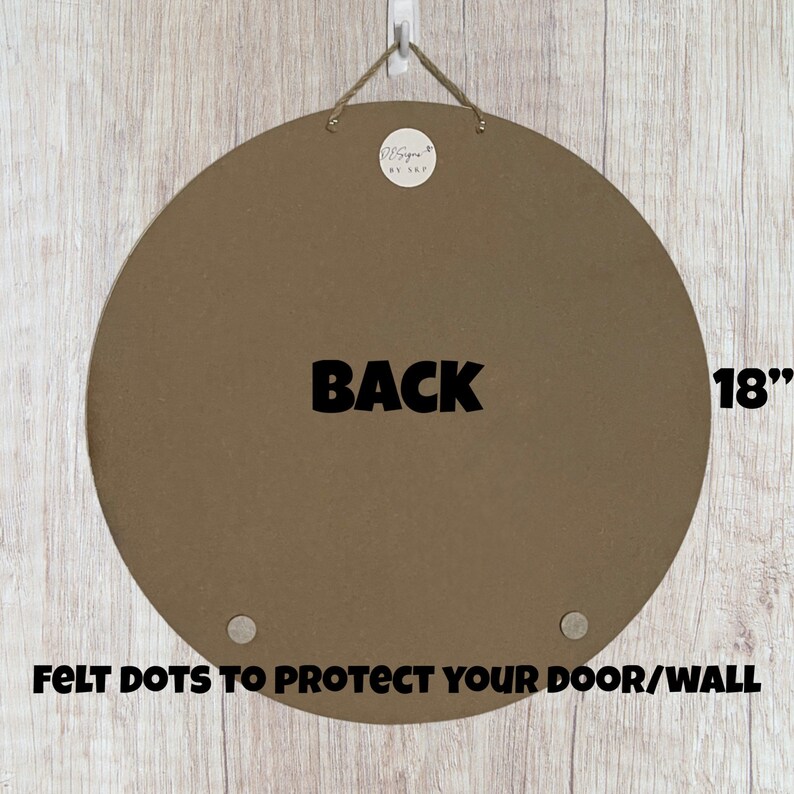 Puede incluir: La parte posterior de una pizarra de fieltro redonda de color marr&oacute;n de 45,7 cm con la palabra "BACK" impresa en negro. La pizarra tiene dos puntos de fieltro para proteger tu puerta o pared.