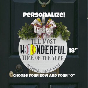 Puede incluir: Un colgador de puerta redondo de madera blanca de 45,7 cm con el texto "The Most Wonderful Time of the Year" y un gr&aacute;fico de softbol. El colgador de puerta est&aacute; decorado con un lazo rojo y blanco con un patr&oacute;n de softbol. El texto "&iexcl;Personalizar!" est&aacute; en la parte superior de la imagen y el texto "Elige tu lazo y tu "O"" est&aacute; en la parte inferior de la imagen.