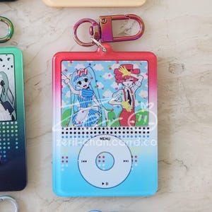 May include: A colorful keychain featuring a cartoon illustration of two anime characters. The keychain has a gradient blue and red border, a silver clasp, and the text "MENU" at the bottom.