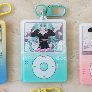 May include: A teal and white keychain featuring a cartoon character with teal hair and a black top. The keychain has a teal and white iPod design with the text "zerii-chan.card.co".