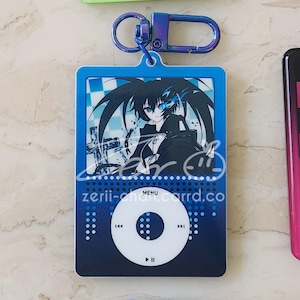 May include: A blue keychain featuring a stylized anime character design. The keychain has a blue carabiner clip and a rectangular pendant with a character illustration, a circular control design, and the text "zerii-chan.carrd.co".