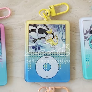May include: A keychain with a yellow and blue gradient design, featuring a cartoon character illustration. The keychain has a yellow clasp and the text "zeriichan.card.co". The design resembles a music player.