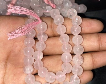 Può includere: Una collana di perle di quarzo rosa con un fiocco rosa ad ogni estremità. Le perle sono rotonde e lisce, e la collana è lunga circa 45 cm.