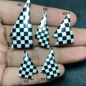 May include: Five black and white checkered triangle-shaped decorative pieces. Each piece has a pointed top and a checkered pattern. The pieces are numbered 01 through 05. The pieces are held in a hand.
