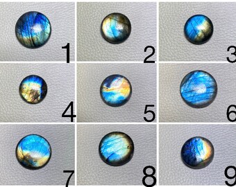Op de afbeelding: Negen ronde, iriserende labradorit-cabochons, elk met een uniek patroon van blauw, groen en goud. De cabochons zijn gerangschikt in een raster van drie rijen en drie kolommen.