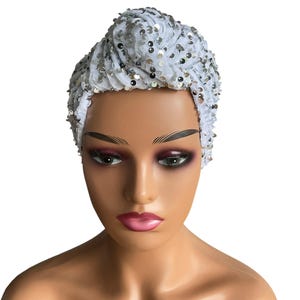 Peut inclure: Un turban blanc orné de sequins argentés. Le couvre-chef est fait d'un tissu doux et texturé. Les sequins ajoutent une touche d'éclat à l'accessoire. Conçu pour être porté sur la tête.