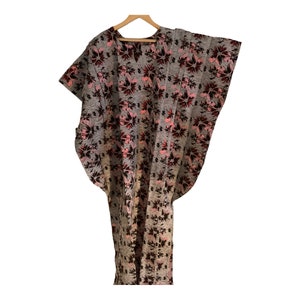 May include: A gray and pink floral print kaftan with short sleeves. The kaftan has a loose fit and is made of a soft, comfortable fabric.