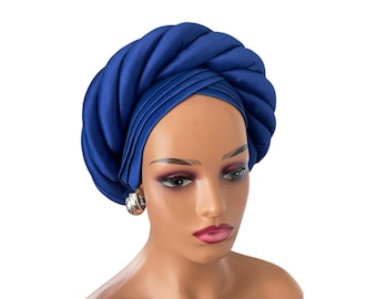 May include: A royal blue satin turban headwrap with a twisted design. The turban is worn on a mannequin head.