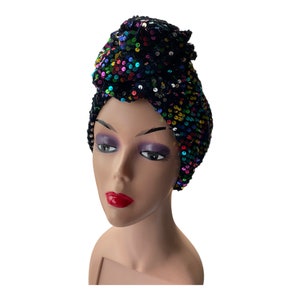 Pode incluir: Um turbante preto com lantejoulas coloridas. O turbante é usado em uma cabeça de manequim.