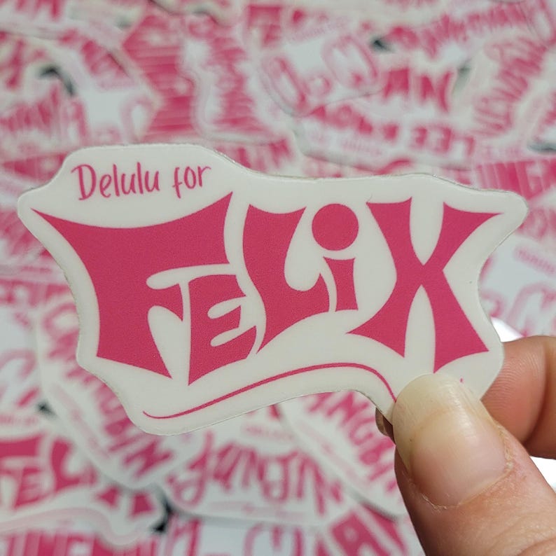 May include: Pink sticker with the text "Delulu for Felix" in a stylized font. The sticker is on a white background and has a glossy finish.