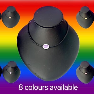 May include: A black necklace with a small, round pendant featuring the word "love" in a purple heart. The image shows the necklace on a black display, with other necklaces on black displays. The background is a rainbow gradient, with the text "8 colours available".