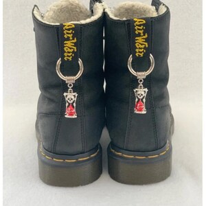 May include: Black leather boots with a fur lining and a silver charm with a skull and hourglass design. The boots have the text "Air Weir" embroidered on the back.