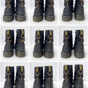 May include: Several pairs of black ankle boots with gold-tone charms. Each boot has a unique charm, such as moons, stars, and dragonflies. The boots have yellow stitching and the text "Air Wair" on the pull tab.