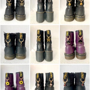 May include: Nine pairs of black and purple Doc Martens boots with gold charms attached to the laces. The charms include a butterfly, a sunflower, a flamingo, and a heart.