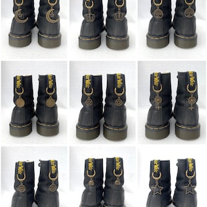May include: Nine pairs of black leather boots with gold charms attached to the laces. The charms feature various symbols, including a crescent moon, a crown, a tree, a pentagram, a flower, a star, and a skull. The boots have yellow stitching and the text "Air Wait" on the back.