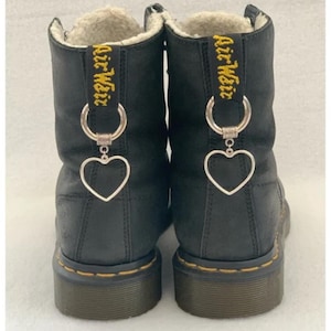 May include: Black leather boots with yellow embroidered text that says "Air Weir" on the back of each boot.  Each boot has a silver heart charm attached to a silver ring.