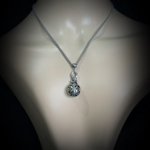 May include: A silver chain necklace with a silver pendant featuring a round, openwork design. The pendant has a floral pattern.