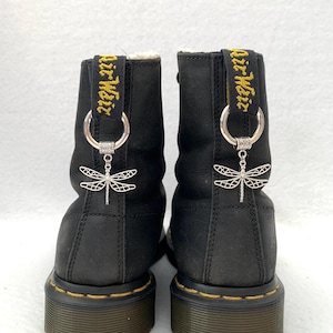 May include: Black leather boots with yellow "Air Wair" straps and silver dragonfly charms. The boots have a black sole and yellow stitching.