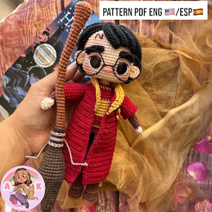 Puede incluir: Muñeco de ganchillo de un personaje con pelo negro, gafas redondas y una cicatriz de rayo. El muñeco lleva una túnica roja y dorada y sostiene una escoba marrón. El texto "PATTERN PDF ENG /ESP" es visible en la imagen.