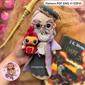Puede incluir: Muñeca de ganchillo hecha a mano de un mago con una larga barba blanca, gafas y una túnica morada, sosteniendo un pájaro rojo y amarillo. La muñeca está junto a un libro titulado "Harry" y el texto "Pattern PDF ENG ESP".