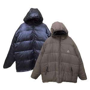 May include: Two puffer jackets with hoods and front zippers. One jacket is dark navy blue with a small rectangular logo patch on the chest. The other jacket is a muted taupe brown featuring a small triangular logo on the chest and two zippered pockets.