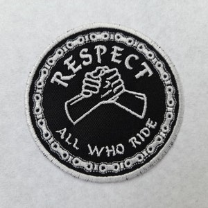 Könnte beinhalten: Ein gestickter Patch in Schwarz und Weiß mit einem Kettengliederrand. Der Patch zeigt zwei ineinander verschlungene Hände und den Text "RESPECT ALL WHO RIDE".