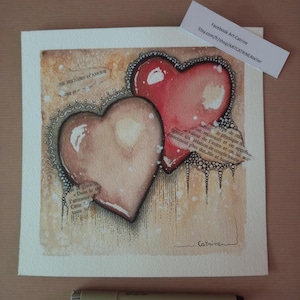 May include: Watercolor painting featuring two hearts, one red and one peach, with a vintage paper background. The hearts are outlined with black lace-like details. Text fragments are visible, adding a layered effect. The artist's signature is at the bottom.